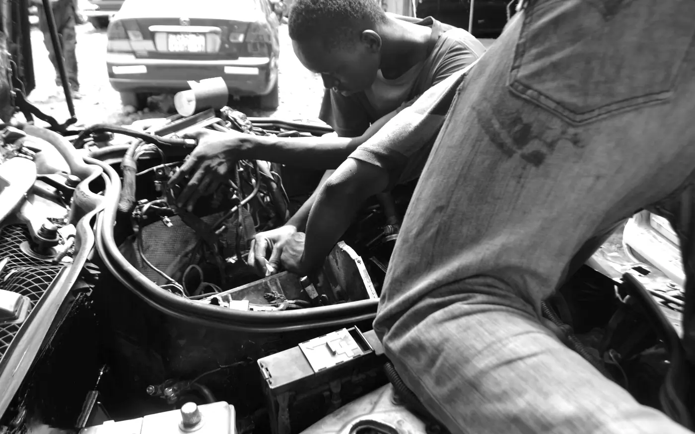 Monteur die over de motorruimte gebogen aan het werk is.